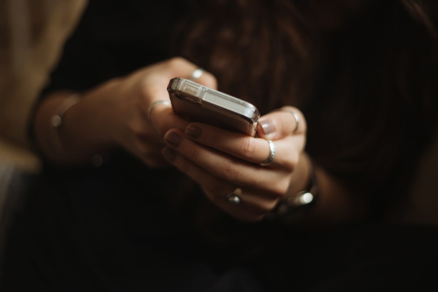 Hands holding a smartphone against a dark background