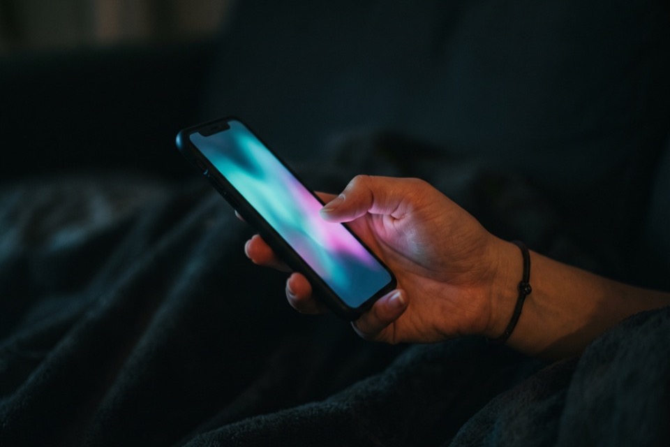A hand holding a glowing phone up close