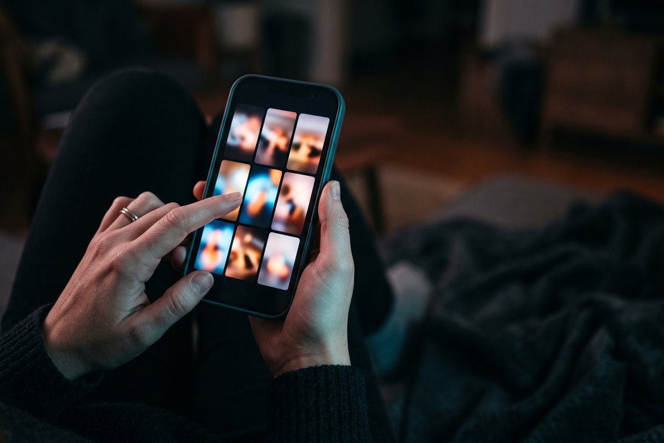 A hand reviewing a grid of reposted videos on a phone