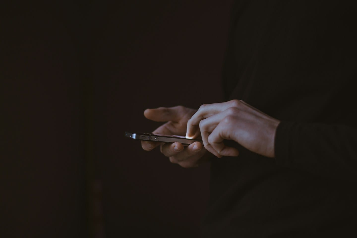A person holding a smartphone in a dark room